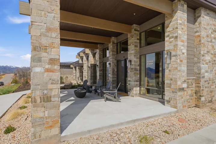 Expansive covered outdoor patio featuring stone columns, a concrete surface, and large format windows