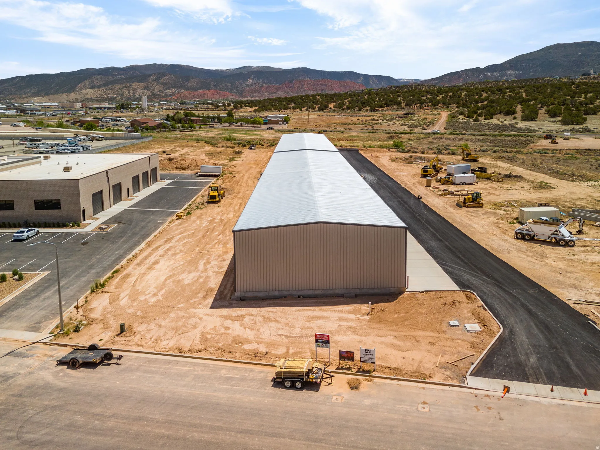 Expansive industrial property featuring a newly constructed metal building with a light-colored roof