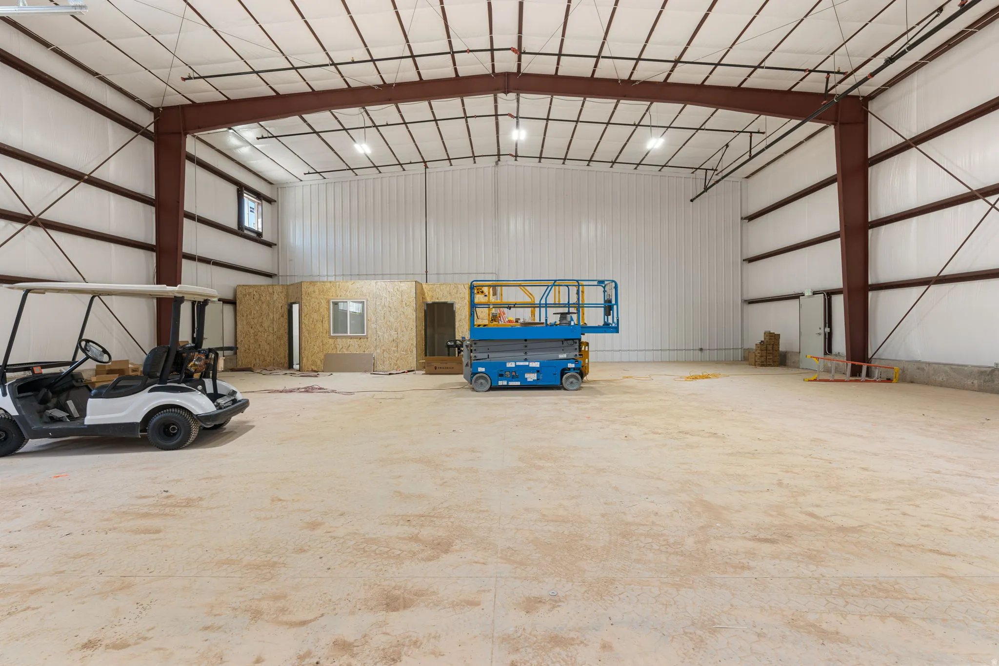 Spacious open-concept commercial interior featuring exposed steel I-beams, a high vaulted ceiling, and concrete flooring