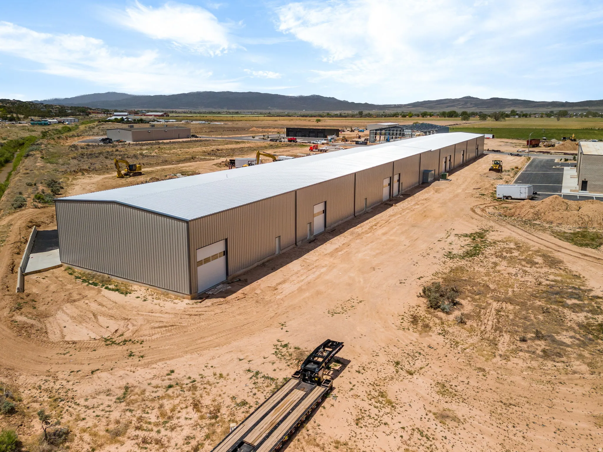 Expansive industrial building featuring multiple roll-up doors, numerous personnel entry points, a metal roof, and durable metal siding