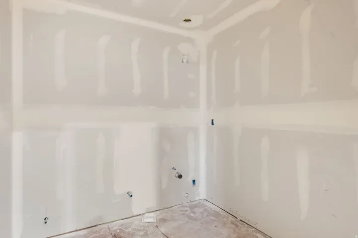 Unfinished interior space with drywall installation, exposed utility connections, and a concrete subfloor