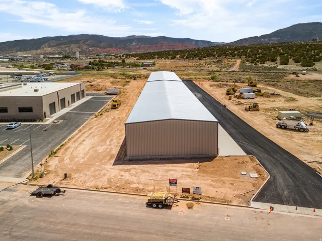 Expansive industrial property featuring a newly constructed metal building with a light-colored roof