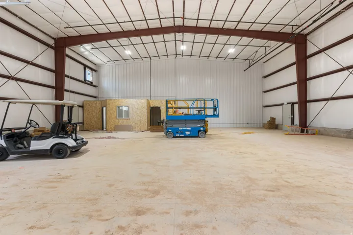 Spacious open-concept commercial interior featuring exposed steel I-beams, a high vaulted ceiling, and concrete flooring