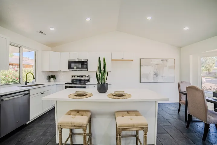 Kitchen featuring white cabinetry, stainless steel appliances, a center island, and dark tile flooring