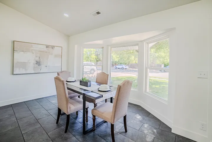 Dining area featuring a bay window, vaulted ceiling, and large format tile flooring
