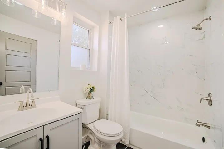 Bathroom featuring a single vanity with shaker-style cabinetry, a built-in sink, and a modern light fixture