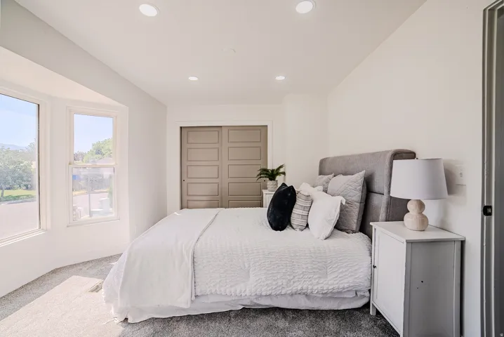 Bedroom featuring recessed lighting, a bay window with multiple panes, gray carpeting, and bi-fold closet doors with panel detailing