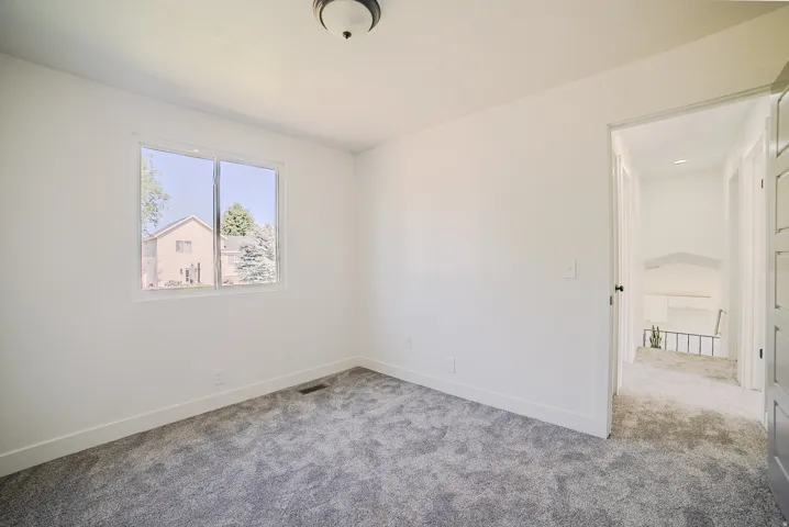 Bright room featuring a window overlooking residential properties and trees