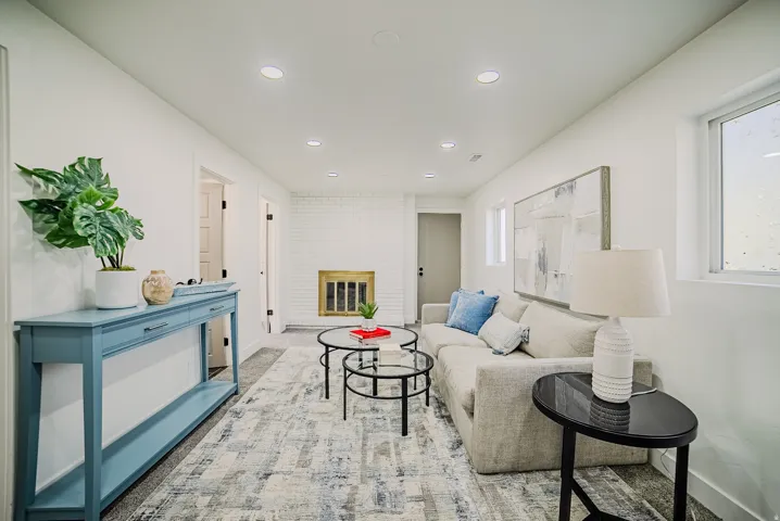 Spacious living area featuring a white painted brick fireplace with a brass-toned grate, recessed lighting, and light-toned walls