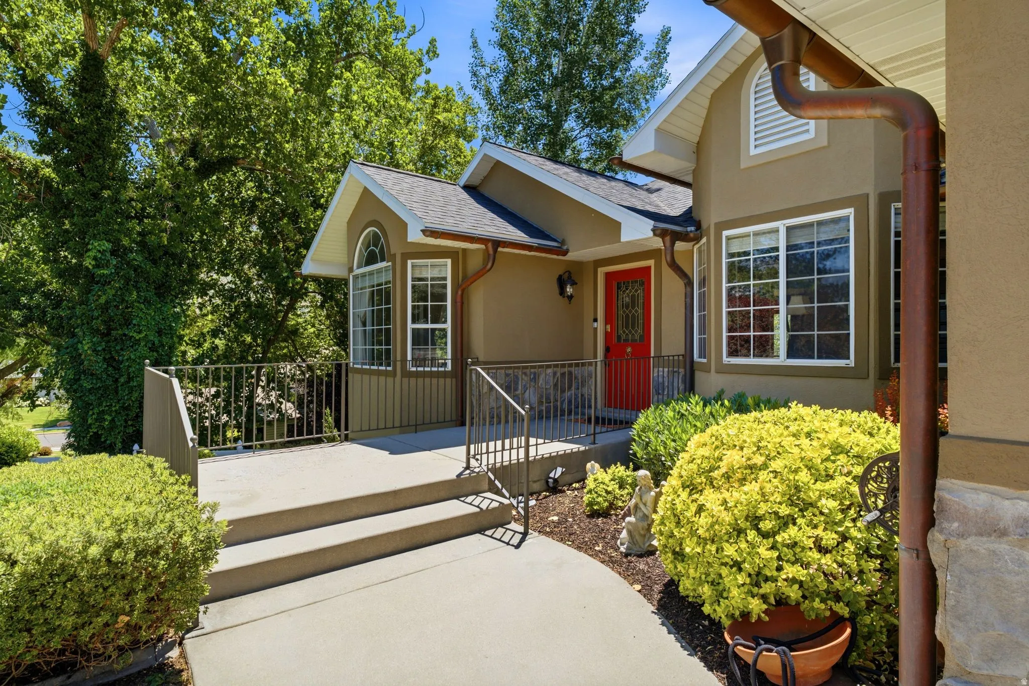Stucco exterior with a red entry door, white-framed windows, and dark-colored gutters