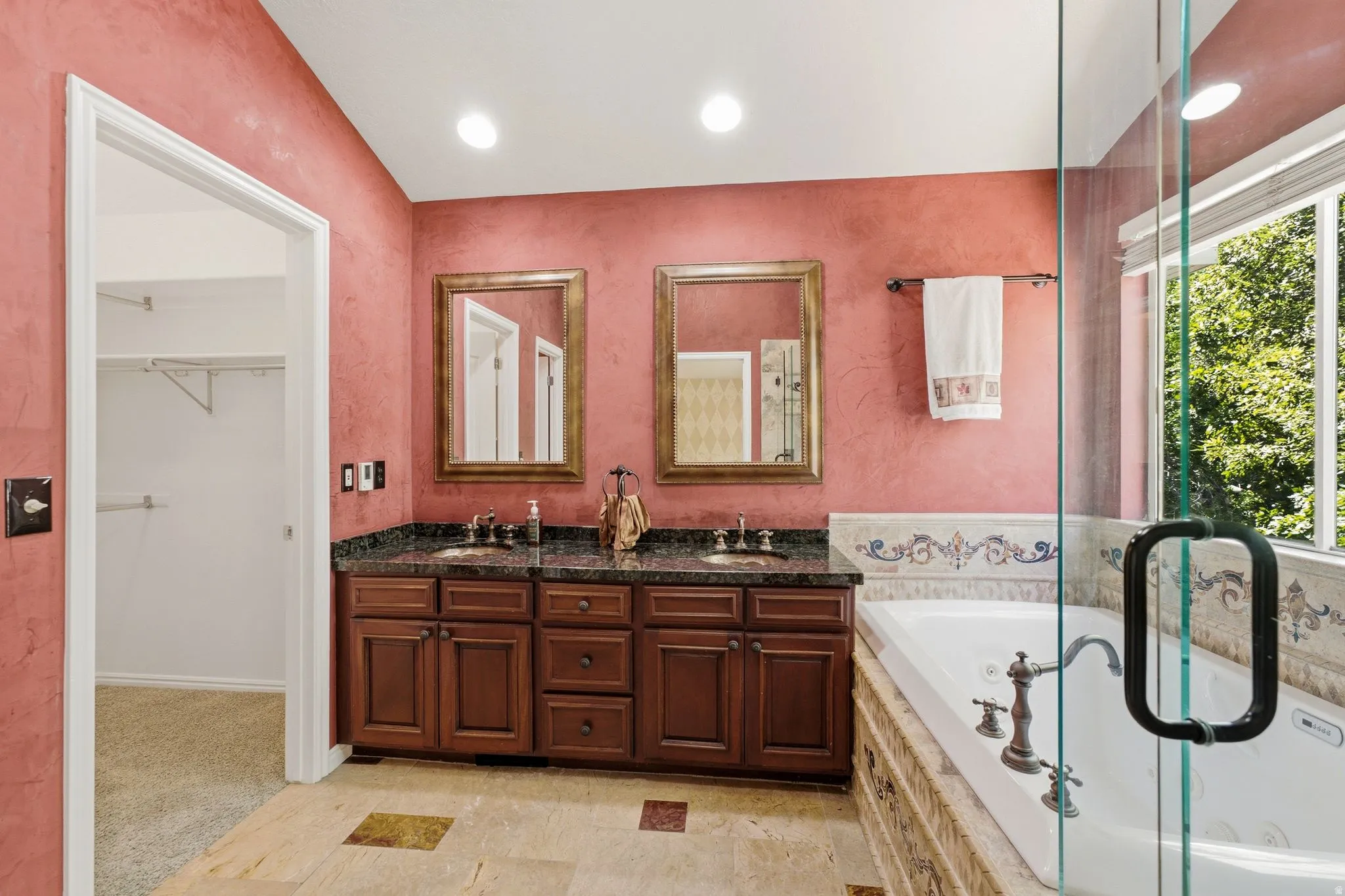 Bathroom featuring a dual vanity with a dark granite countertop, a built-in jetted tub, a glass-enclosed shower, and tile flooring