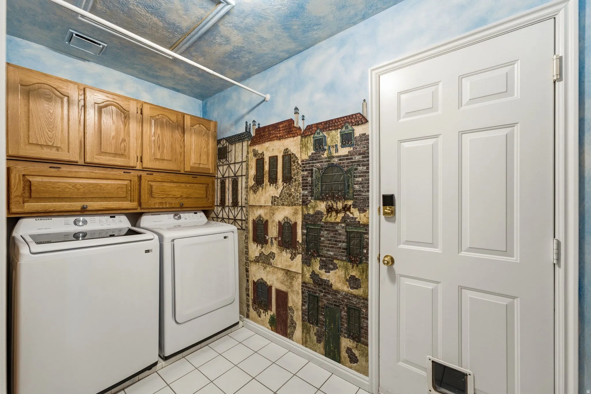 Laundry area with built-in wood cabinetry, white tile flooring, and a white six-panel door