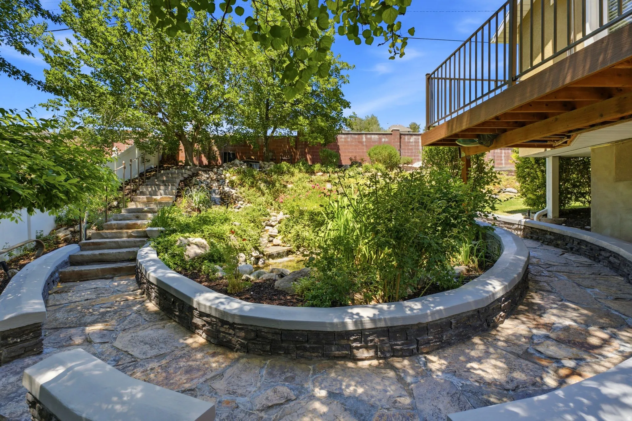 Expansive flagstone patio with a stone-clad planter featuring varied greenery