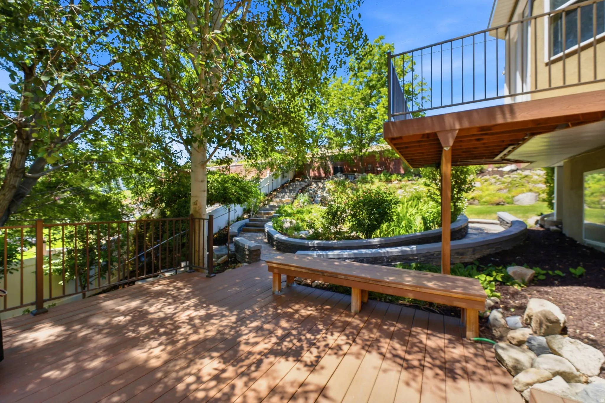 Expansive outdoor deck featuring wood-finish flooring and a built-in wooden bench