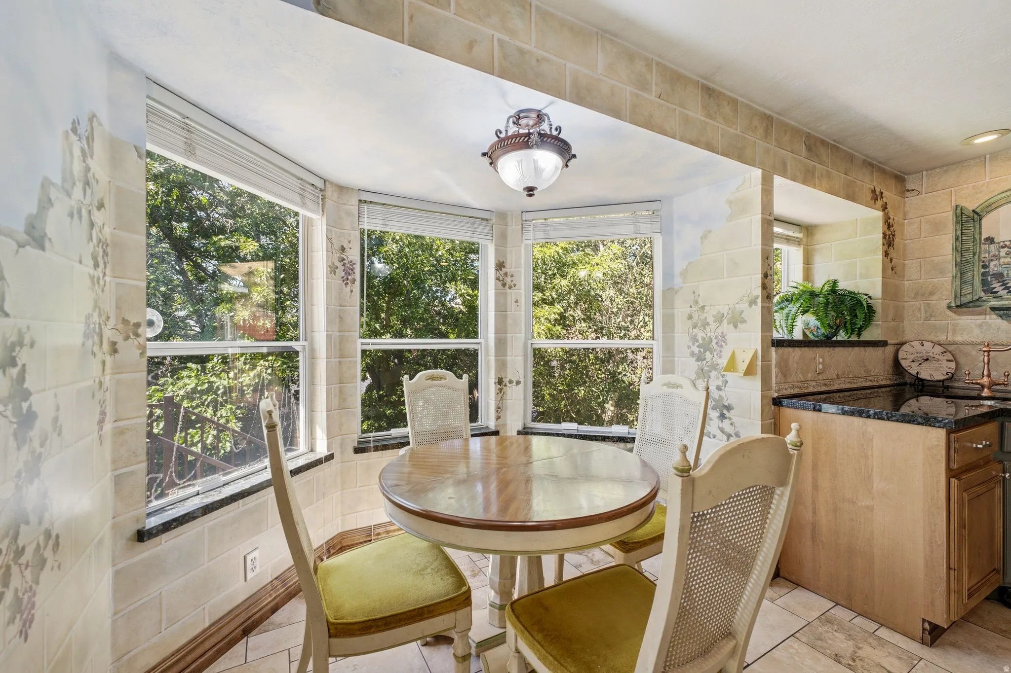 Bay window dining area featuring a wood-finish table, a decorative hanging light fixture, and tiled flooring