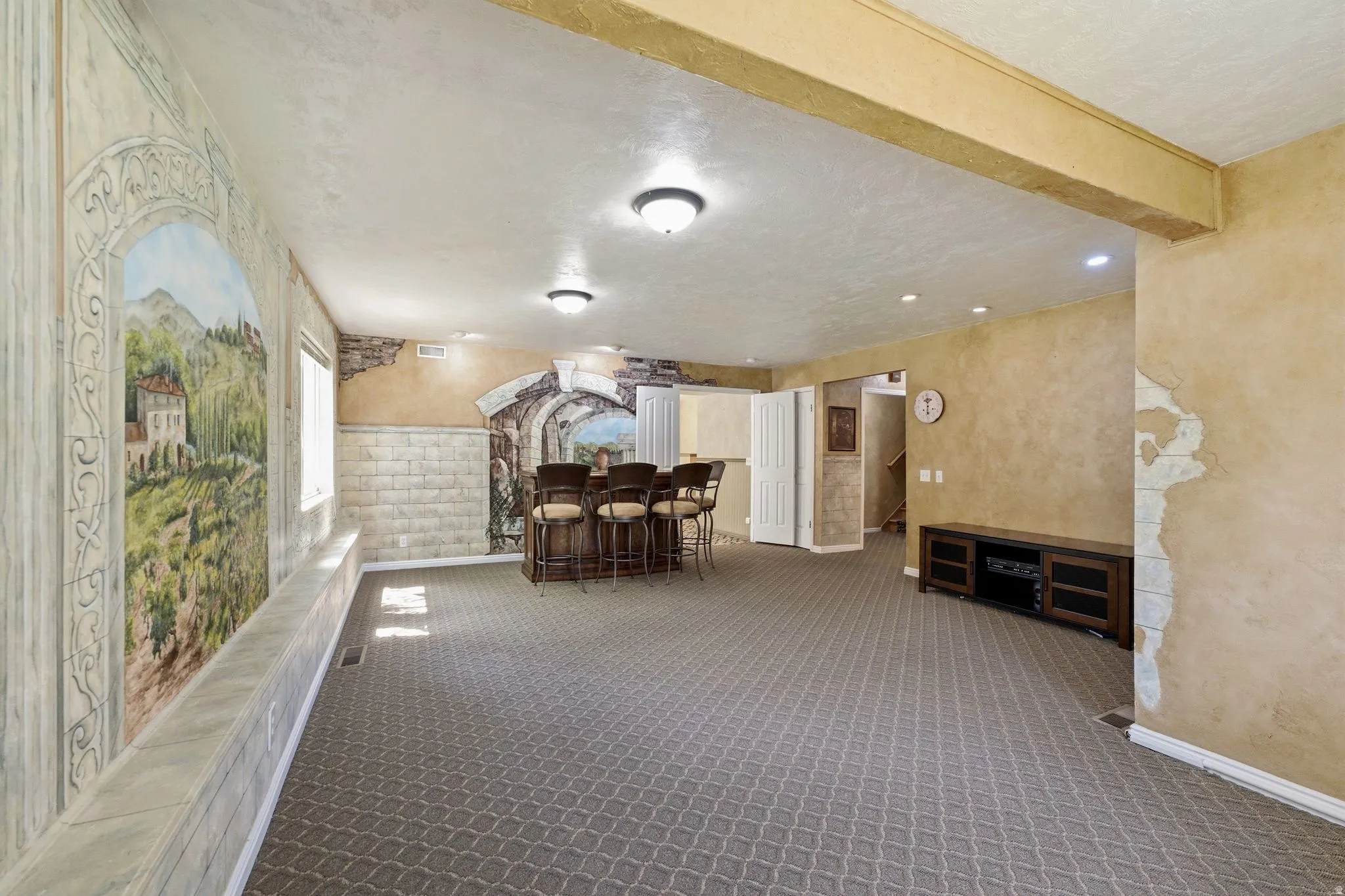 Spacious room featuring patterned carpet flooring, recessed lighting, and a built-in bar with seating for four