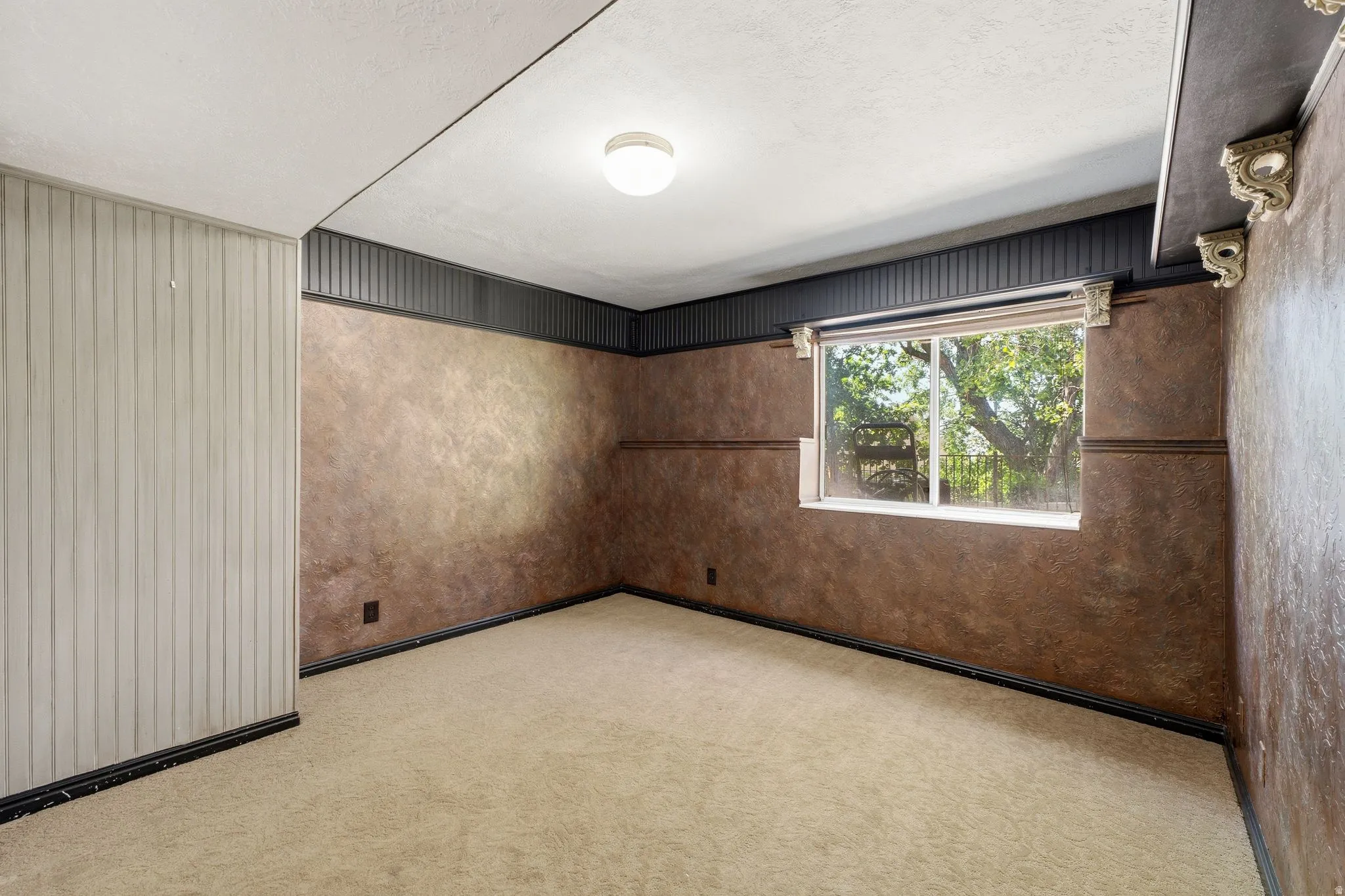 Carpeted room featuring a single window, a fluted wall accent, textured wall finishes, and a flush mount ceiling light fixture