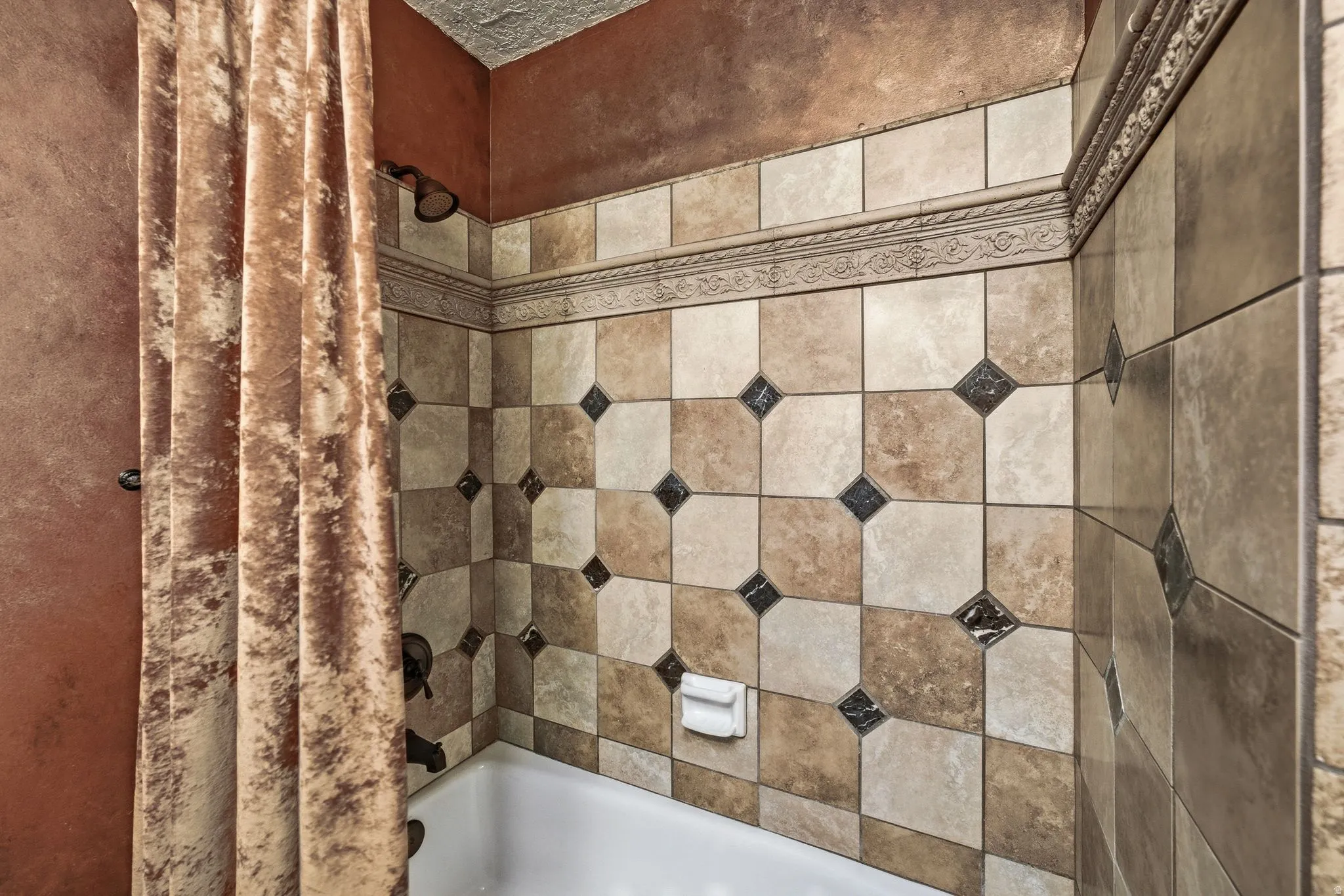 Tub and shower combination featuring patterned tile surround with decorative trim
