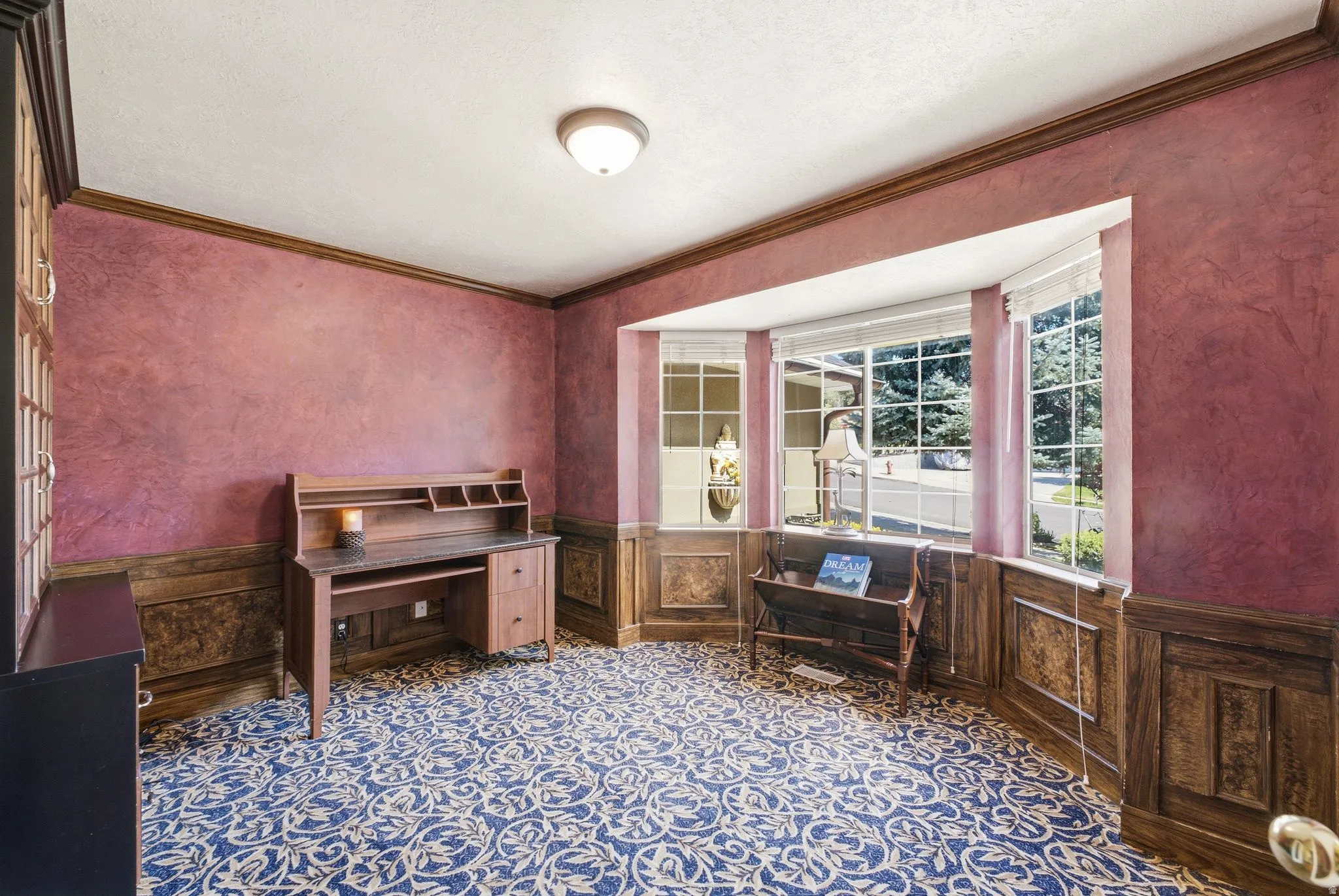 Bay window with multiple panes, wood-paneled wainscoting, and patterned carpet flooring