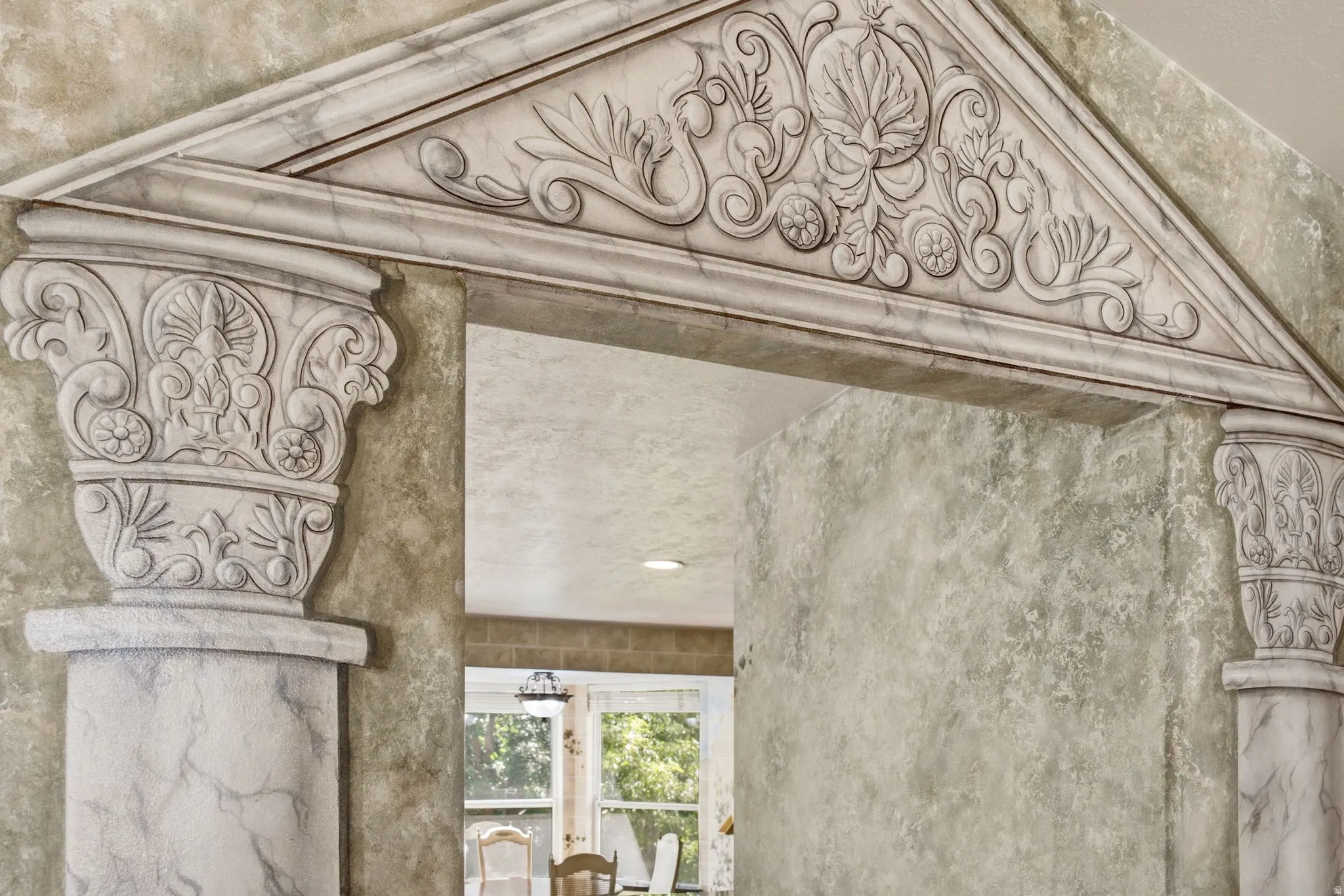 Archway with ornate pediment and decorative column capitals, featuring a marble-finish texture