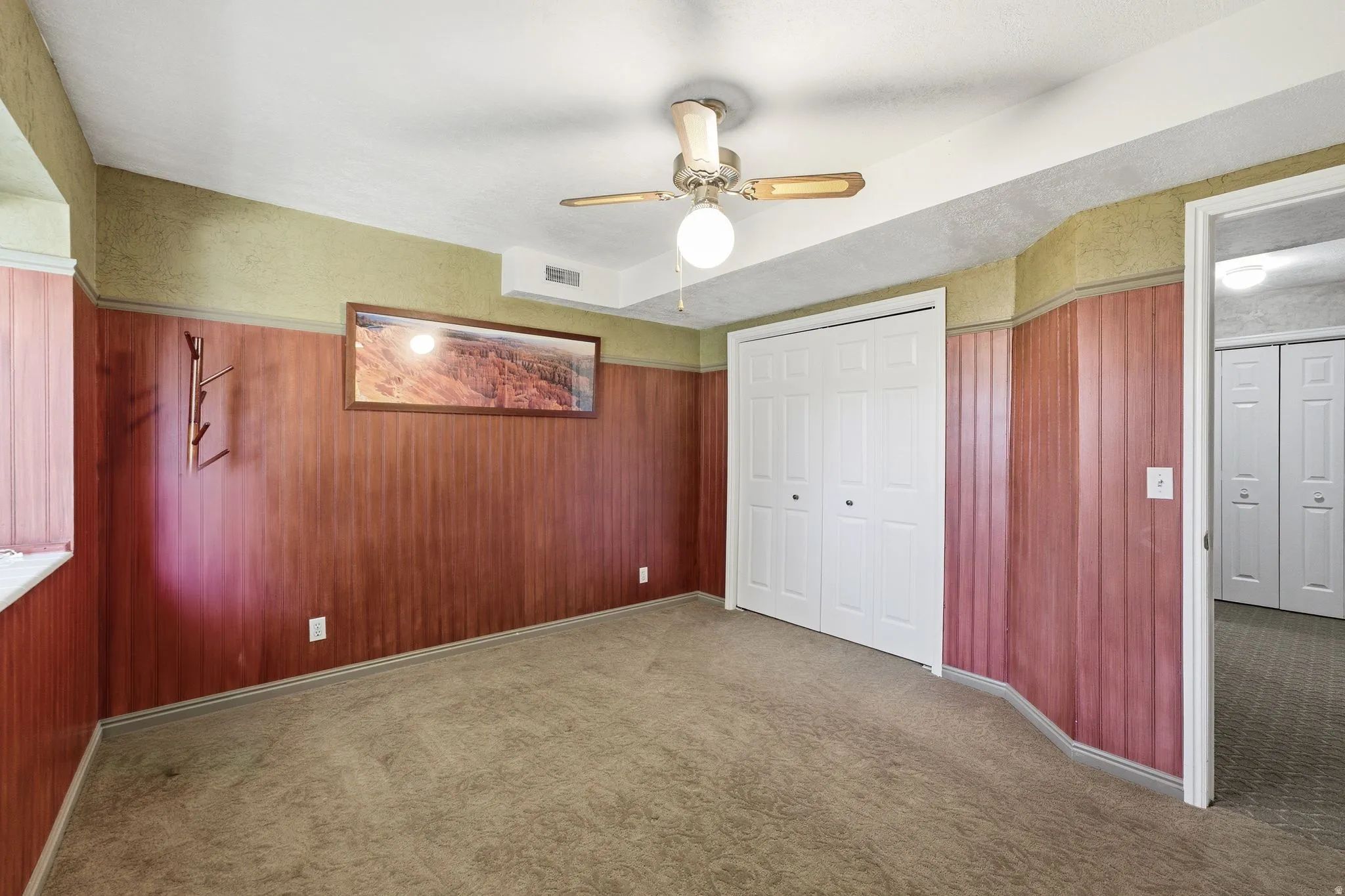 Carpeted room with wood paneling and a drop ceiling