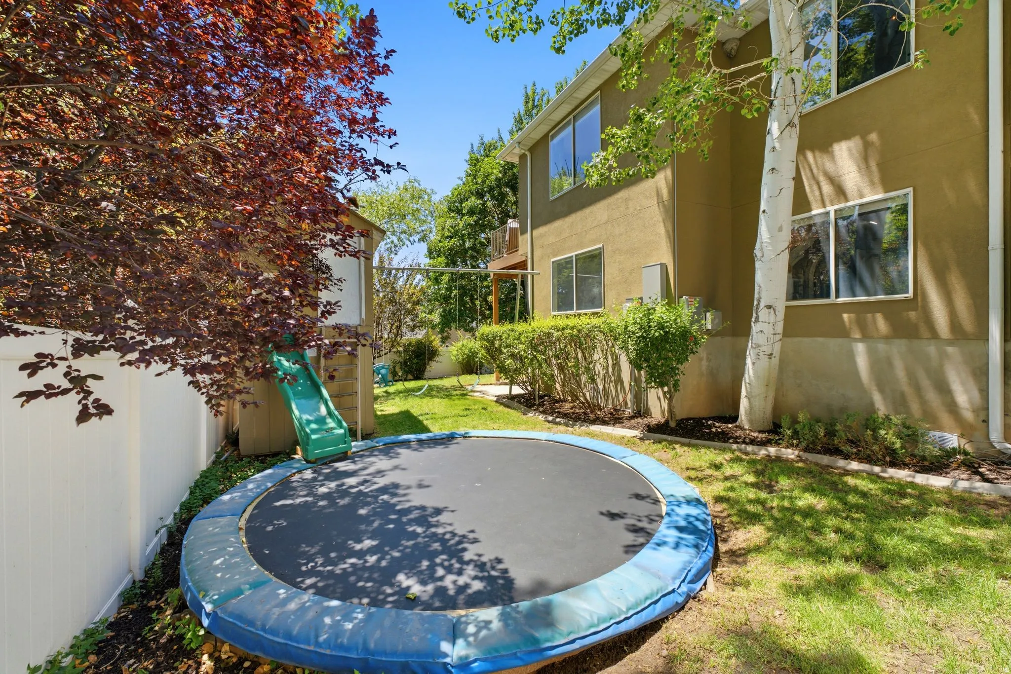Expansive backyard featuring a manicured lawn, established trees, and a privacy fence