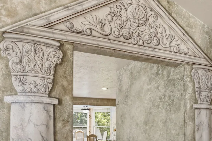 Archway with ornate pediment and decorative column capitals, featuring a marble-finish texture