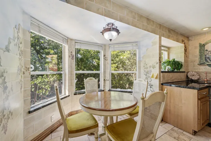 Bay window dining area featuring a wood-finish table, a decorative hanging light fixture, and tiled flooring