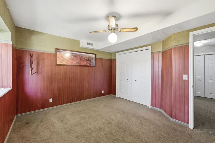 Carpeted room with wood paneling and a drop ceiling
