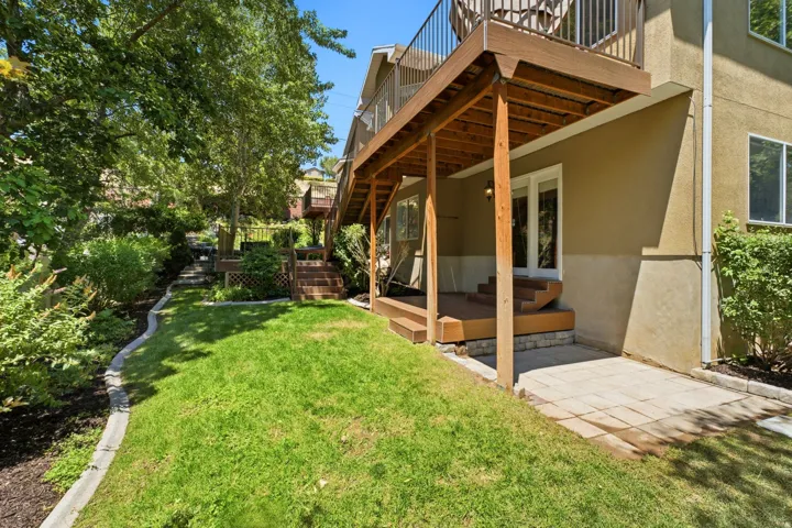 Expansive backyard featuring a manicured lawn, established landscaping, and a multi-level wooden deck