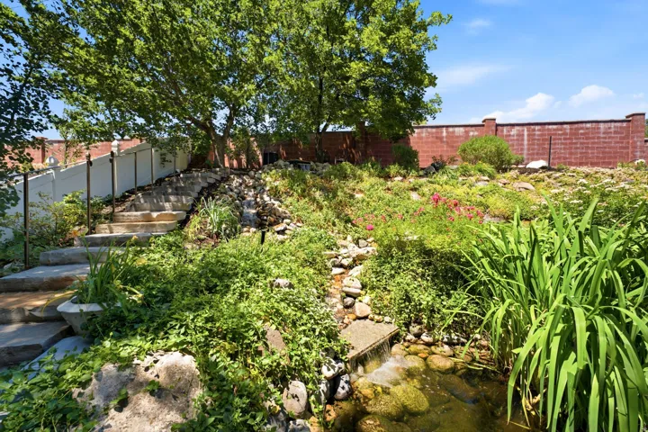 Tiered landscaping with stone steps and handrails ascending a verdant incline