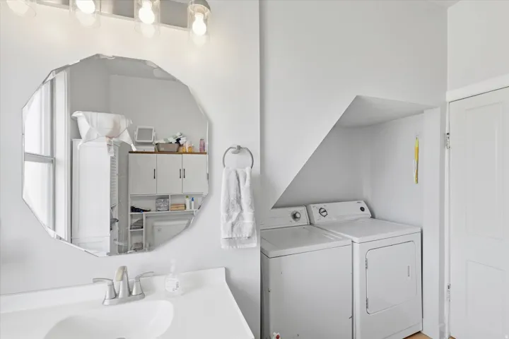 White vanity with integrated sink, chrome faucet, and decorative octagonal mirror