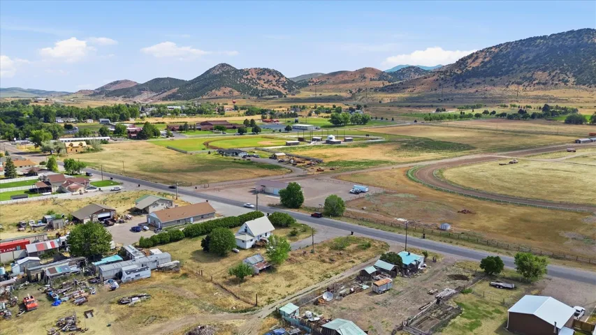 Expansive rural landscape featuring a paved road, scattered residential structures, and distant mountains under a clear sky