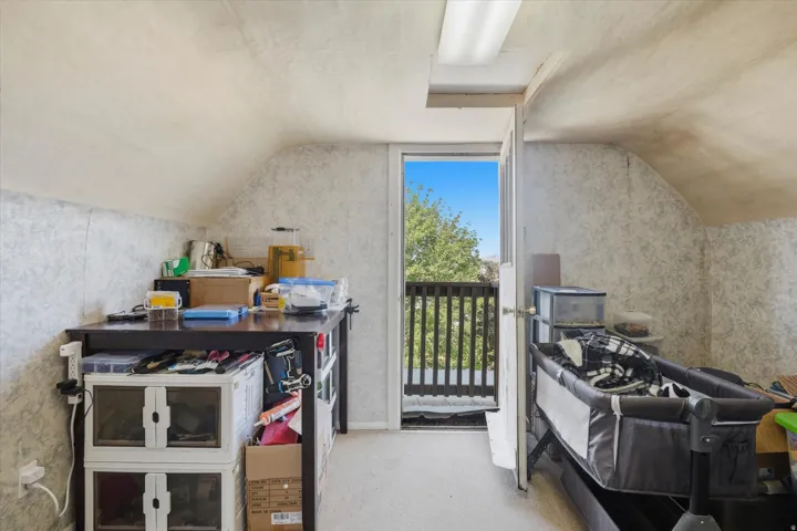 Attic space featuring sloped ceilings, textured wall finishes, and carpet flooring