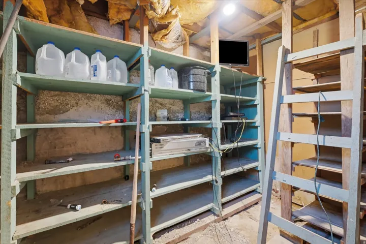 Utility space featuring exposed insulation, wood framing, and built-in shelving units