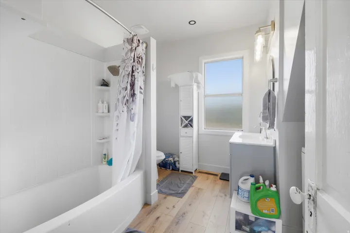 Bathroom featuring a white subway tile surround, wood-finish flooring, and a single window