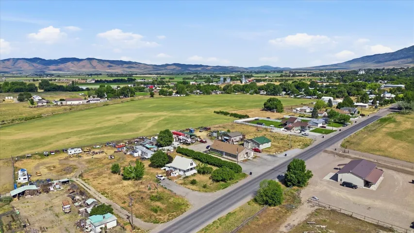 Expansive rural landscape featuring a mix of residential structures, open fields, and distant mountains under a clear sky