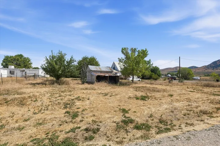 Expansive open land featuring mature trees and distant mountain ranges
