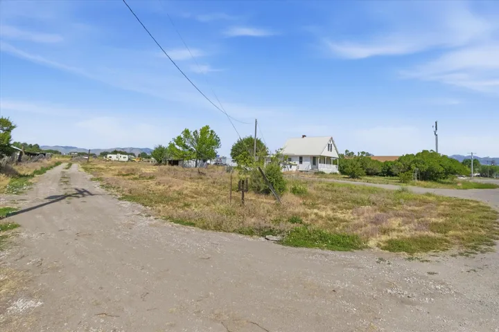 Expansive lot featuring a gravel road, natural landscaping, and distant mountain ranges