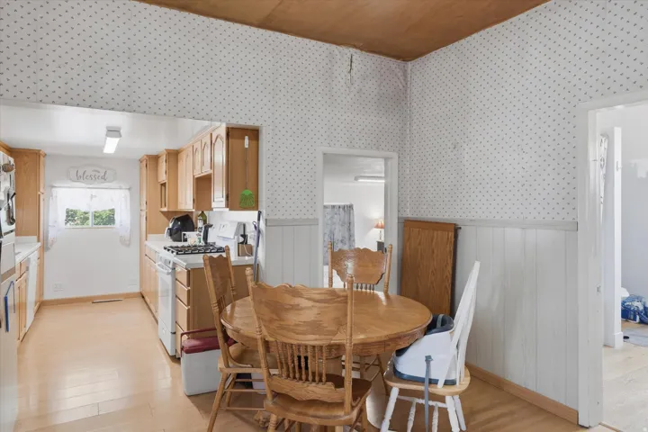 Compact kitchen featuring wood-finish cabinetry, white countertops, and white appliances including a range