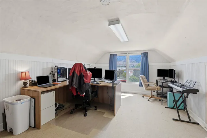 Carpeted room featuring sloped ceilings, beadboard wall paneling, and a large window