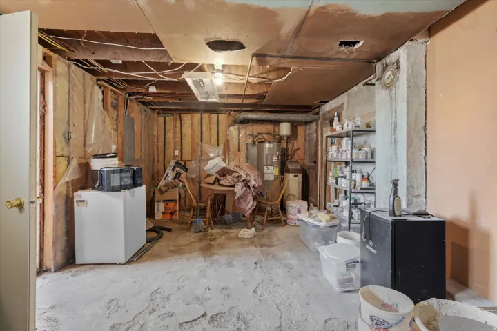 Unfinished basement space featuring exposed wooden framing, concrete flooring, and visible utility lines