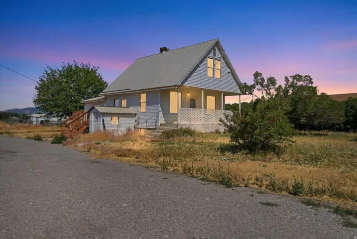 Light blue siding exterior featuring a metal roof, prominent front porch with lattice detailing, and a dormer window