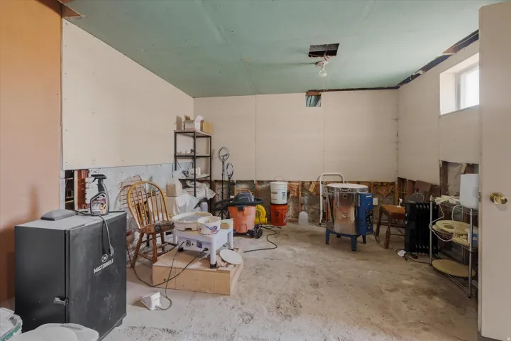 Unfinished interior space with exposed concrete flooring, partial drywall installation, and a single window