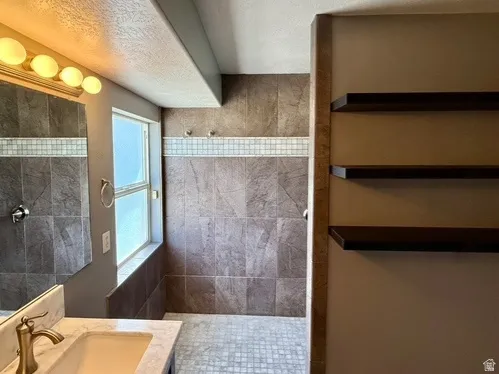 Tiled shower with decorative accent band, mosaic tile flooring, and integrated window