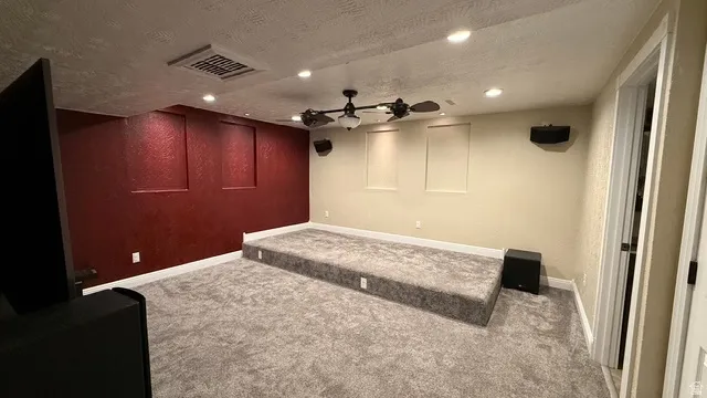 Carpeted room with elevated platform, recessed lighting, and ceiling fan