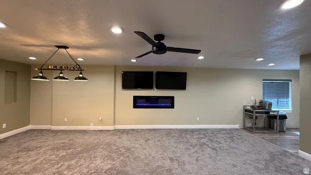 Recessed lighting, ceiling fan, built-in electric fireplace, wall-mounted television, and wood-finish flooring