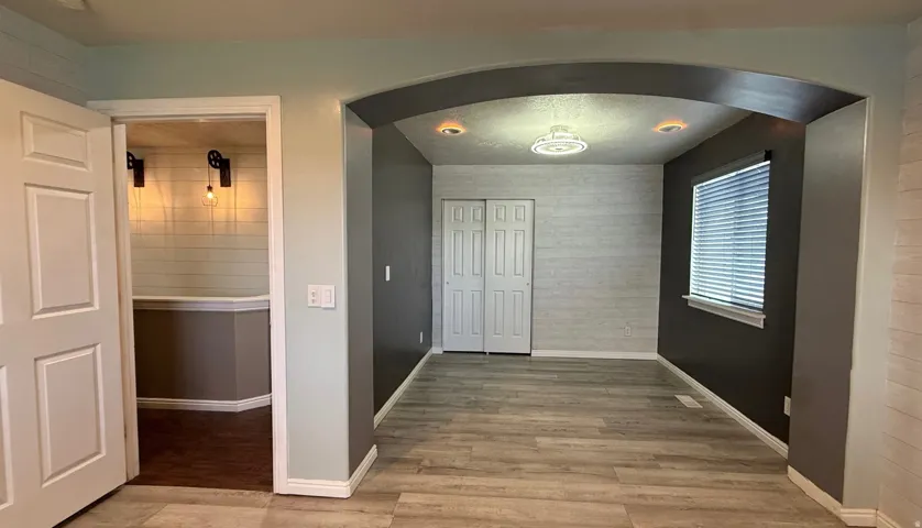 Master Bedroom -Wood-finish flooring throughout, framed by an arched doorway