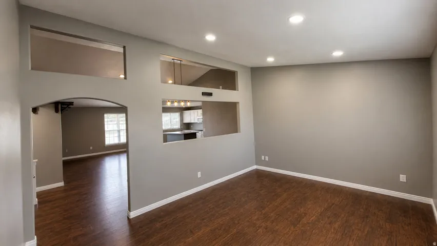 Recessed lighting, wood-finish flooring, arched doorway, pass-through window, and light gray walls