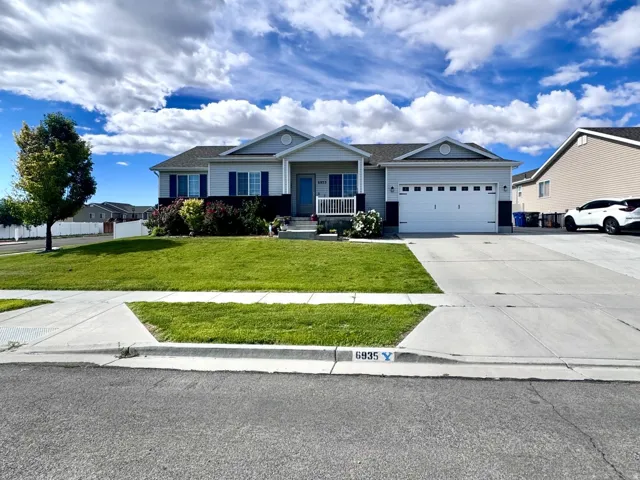 Ranch-style residence featuring a light gray exterior with dark blue window shutters, an attached two-car garage with a white door, and a covered front porch entry
